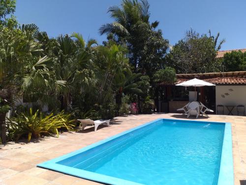 a swimming pool in a yard with an umbrella at Residencial Coroa Vermelha in Santa Cruz Cabrália