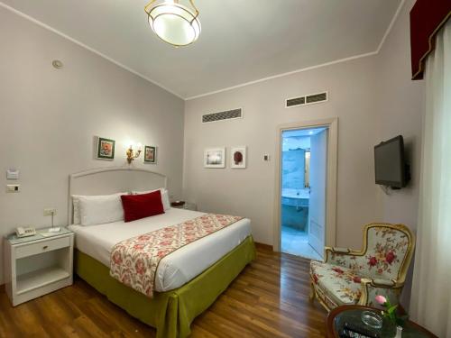 a bedroom with a bed and a chair and a television at San Giovanni Stanly Hotel in Alexandria