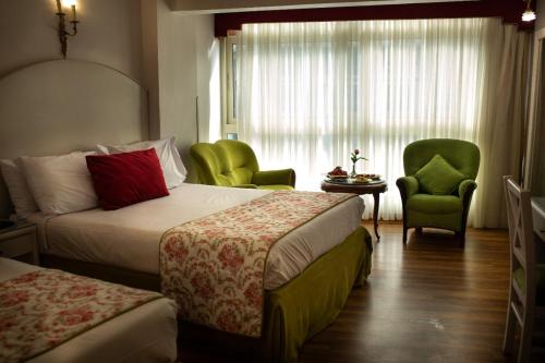 a hotel room with two beds and chairs and a window at San Giovanni Stanly Hotel in Alexandria