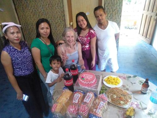 a group of people standing around a table with a cake at SHUKRAN Apartelle in Siquijor