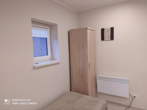 a room with a bed and a cabinet and a window at Dolistówka Apartamenty, pole namiotowe, balia z jacuzzi, ogród warzywny dla gości, plac zabaw dla dzieci in Goniadz