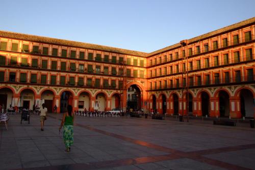 a woman walking in front of a large building at Centro Histórico Mezquita Judería La Preferida in Córdoba