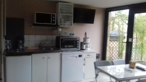 - une cuisine avec des placards blancs, un four micro-ondes et une table dans l'établissement LA ROUGIE, à Yvetot Bocage