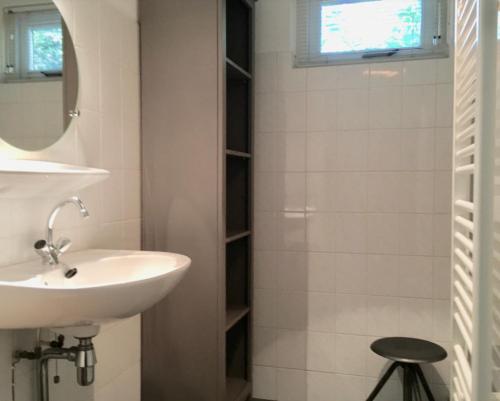 a bathroom with a sink and a mirror and a stool at Natuurhuisje Even Niets in Zelhem