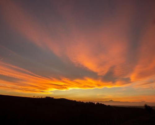 a sunset over a field with a cloudy sky at Ferrarotti in Clavesana