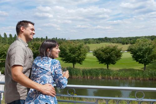 a man and a woman standing on a bridge overlooking a golf course at Mercure Chantilly Resort & Conventions in Chantilly