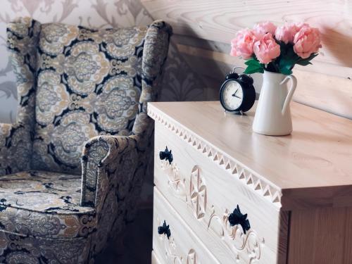 a table with a vase of pink flowers and a clock at Domek Tatrzańska Zyngierka z Jacuzzi in Ząb