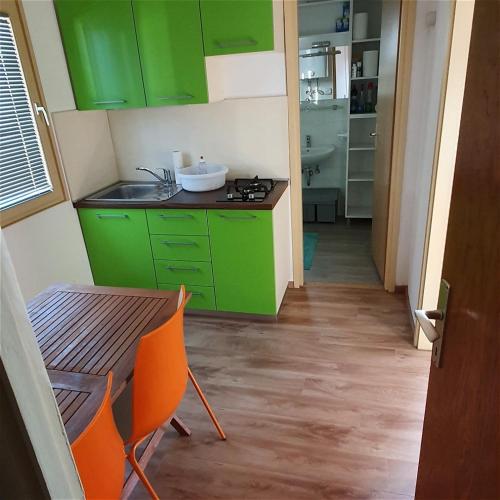 eine Küche mit grünen Schränken und einem Tisch mit Stühlen in der Unterkunft Terme Banovci - Hiška 74 in Banovci