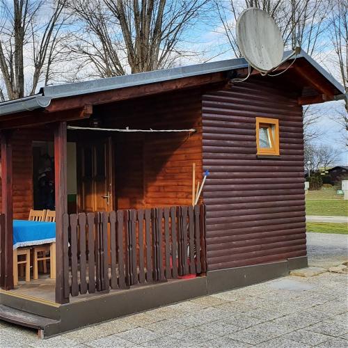 eine kleine Blockhütte mit einer Veranda und einem Fenster in der Unterkunft Terme Banovci - Hiška 74 in Banovci