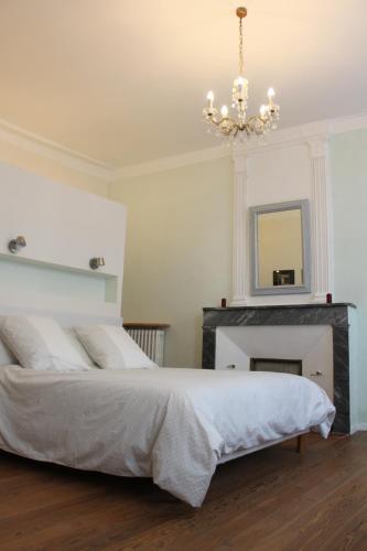 1 dormitorio con 1 cama con chimenea y lámpara de araña en Les loges de la suite, en Prades