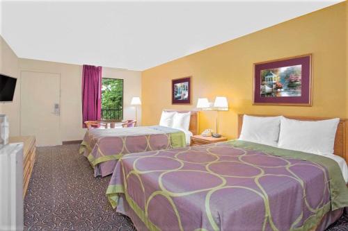 Habitación de hotel con 2 camas y TV de pantalla plana. en Super Inn Williamsburg en Williamsburg