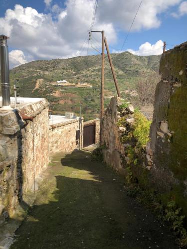 an alley with a stone wall with a mountain in the background at ANOI 1-bedroom country House in Episkopi Pafou