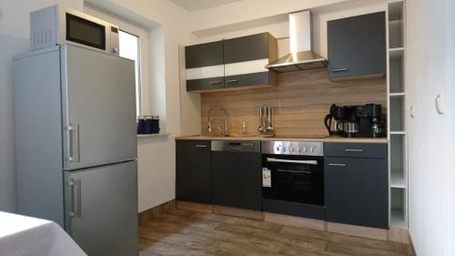 a kitchen with gray cabinets and a refrigerator at Ferienwohnung am Waldchen in Bad Kissingen