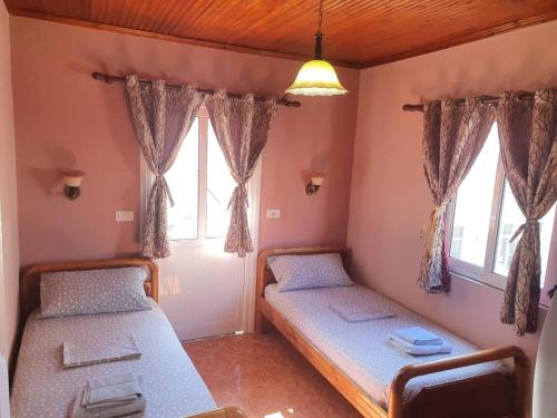 two beds in a room with two windows at Apartment Donend in Berat