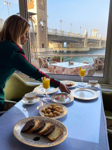 a woman is sitting at a table with food at San Giovanni Stanly Hotel in Alexandria