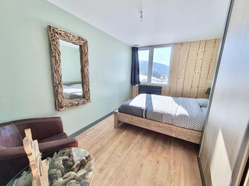 a bedroom with a bed and a mirror and a chair at Les Chamois du Jura à Lajoux in Lajoux