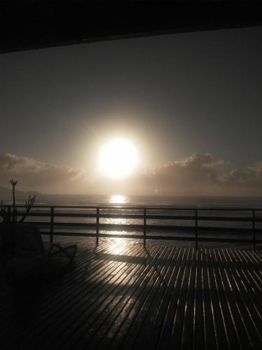 a sun setting over the ocean from a deck at Hibisco Guest House in Florianópolis