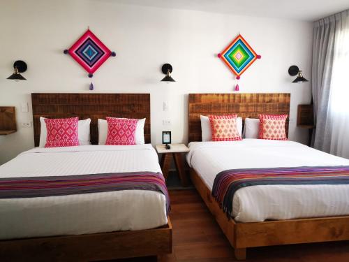 two beds in a hotel room with red and white pillows at Santa Josefita B&B in Cholula