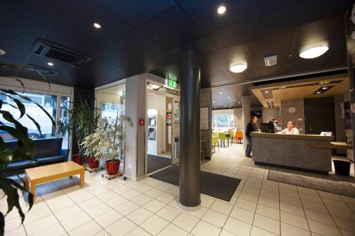 a lobby of a restaurant with a man standing at a counter at ibis budget Flensburg Handewitt in Handewitt