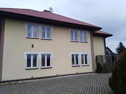 a white house with white windows on a brick driveway at Pokoje Gościnne Strumykowa in Lublin