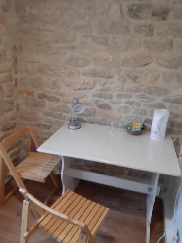 une table blanche, une chaise et un mur en pierre dans l'établissement Chambre d'Hôtes avec Petit Déjeuner, à Remilly-les-Pothées