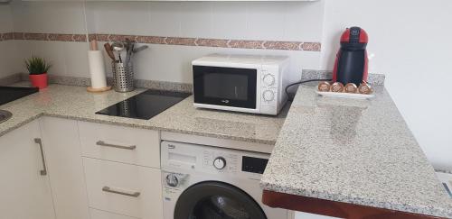 a kitchen with a microwave and a washing machine at Apartamento Conil Centro y Playa, descanso perfecto, con aire acondicionado y WIFI in Conil de la Frontera