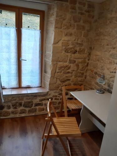 uma mesa e cadeira num quarto com uma parede de pedra em Chambre d'Hôtes avec Petit Déjeuner em Remilly-les-Pothées