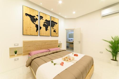 a bedroom with a large bed with four paintings on the wall at Luxury Apartment Salerno Center in Salerno