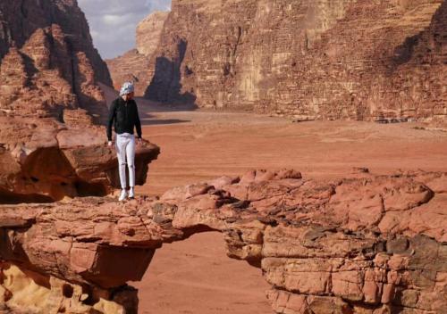 a man standing on a rock in the desert at Wadi Rum in Wadi Rum
