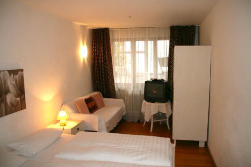 a hotel room with a bed and a couch and a tv at Gasthaus Sonne in Vörstetten