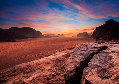 a sunset in the desert with a rock formation at Wadi Rum in Wadi Rum