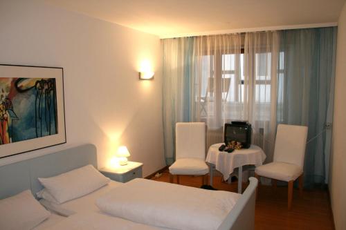 a bedroom with a bed and two chairs and a table at Gasthaus Sonne in Vörstetten