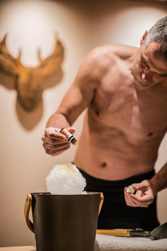 a shirtless man is lighting up a pot of food at Helmhotel in San Candido