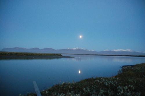 a moon over a body of water at night at Húsey Hostel & Horsefarm in Egilsstadir