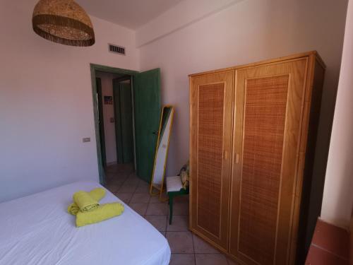 a bedroom with a bed and a wooden cabinet at Villetta con giardino in Residence IN CENTRO in Villasimius