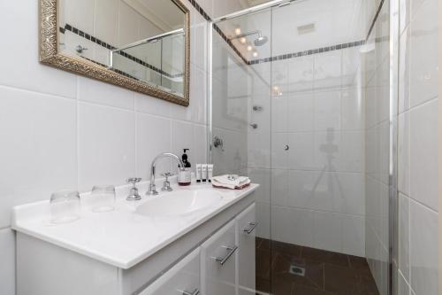 a white bathroom with a sink and a shower at 94Best Apartments in Wagga Wagga