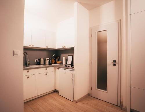 a small kitchen with white cabinets and a door at Latron 98 in Český Krumlov