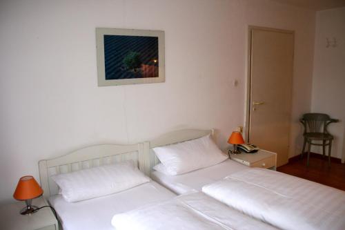 a bedroom with two white beds and a picture on the wall at Gasthaus Sonne in Vörstetten