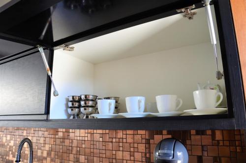 a mirror above a kitchen counter with white cups and saucers at Casa de Luxo na Praia - Sun Luxury Home in Aracaju