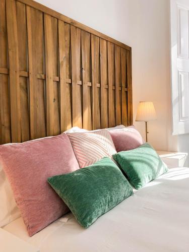 a bed with four pillows on it with a wooden headboard at Casa dos Castelos in Évora