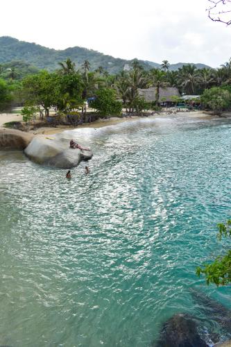 a boat in the water next to a beach at Ecohotel Yachay Dentro del Parque Tayrona Inside Tayrona Park in El Zaino