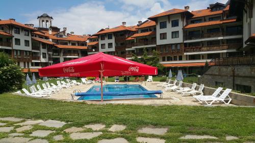 a red umbrella and chairs and a swimming pool at Koko's apartments in Bansko