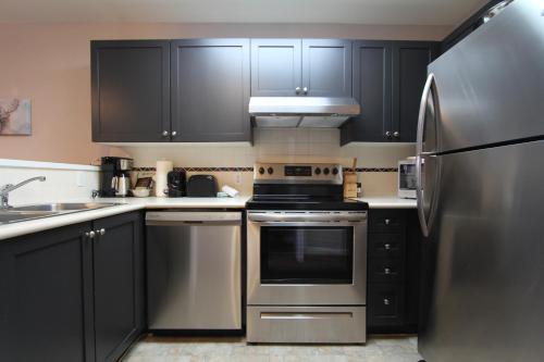 a kitchen with black cabinets and a stainless steel refrigerator at Marketplace Lodge by Whistler Retreats in Whistler