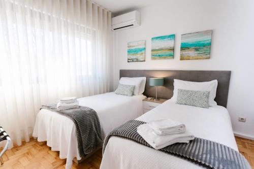 two beds in a bedroom with white walls at Mumadona Apartment in Guimarães