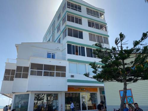 a tall white building with people standing in front of it at Apartamento Vacacional Con Vista Al Mar San Andres in San Andrés