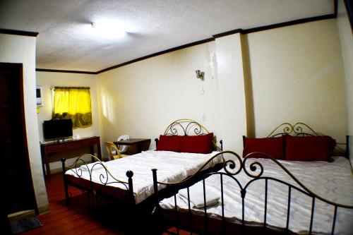 a bedroom with two beds with red pillows at Rufina's Leisure Center in Tagum