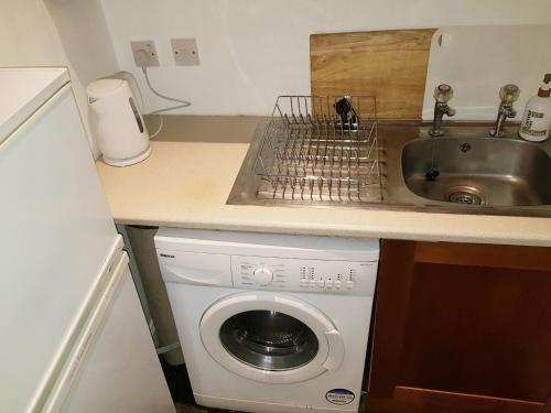 a kitchen with a washing machine and a sink at Glen Valley Self-Catering Apartment in Port Glasgow