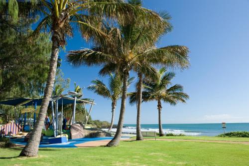 a group of palm trees next to the beach at Nautilus Beachside Apartments in Bargara