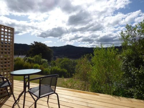 einen Tisch und einen Stuhl auf einer Holzterrasse mit Aussicht in der Unterkunft Kaiteriteri Abel Tasman Inlet Views in Kaiteriteri