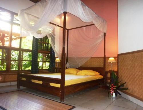 a canopy bed in a room with a window at Saraswati Holiday House in Lovina